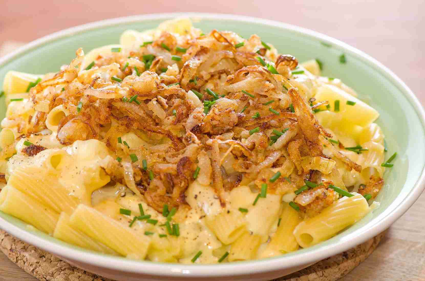 Älplermagronen, makanan khas Swiss yang terdiri dari pasta, kentang, keju leleh, bawang goreng, dan saus apel, disajikan sebagai hidangan tradisional pegunungan Alpen.