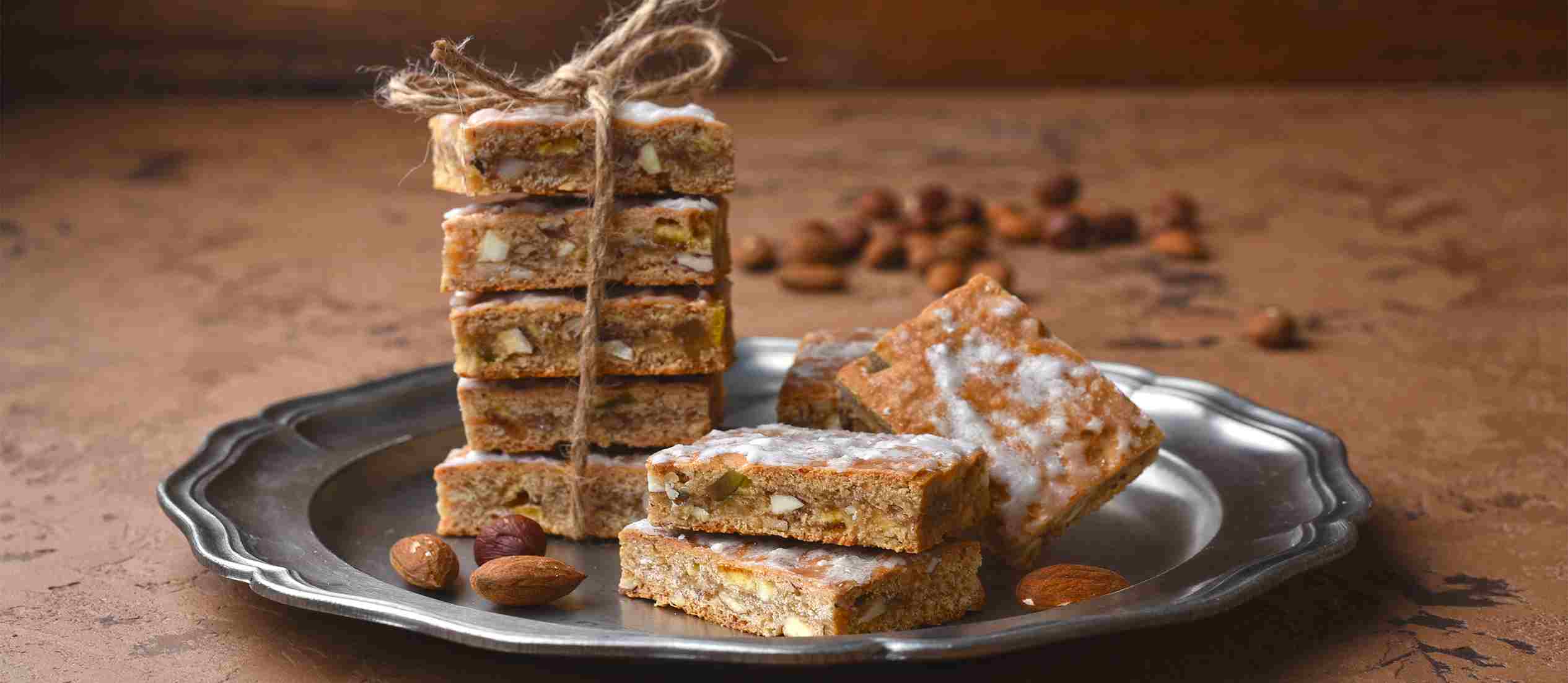 Basler Läckerli, makanan khas Swiss berupa kue tradisional dari Basel dengan rasa madu, kacang, kulit jeruk kering, dan rempah, dipotong persegi dan disajikan sebagai camilan manis khas.