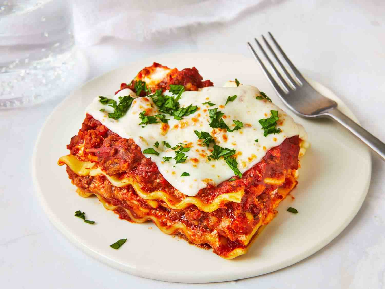 Lasagna, makanan khas Italia berlapis pasta, daging cincang, saus tomat, béchamel, dan keju leleh yang dipanggang hingga berwarna keemasan dan menggugah selera.