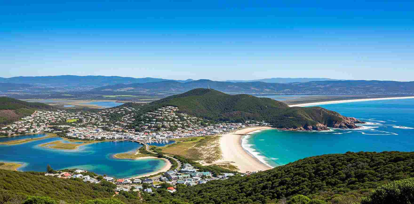 Lanskap Garden Route di Afrika Selatan, menampilkan keindahan alam yang beragam termasuk hutan lebat, garis pantai yang terjal, pantai yang masih asli, dan kota-kota atau laguna yang menawan, di bawah langit yang cerah. Pemandangan ini adalah salah satu alasan mengapa banyak orang memilih wisata di Afrika Selatan.