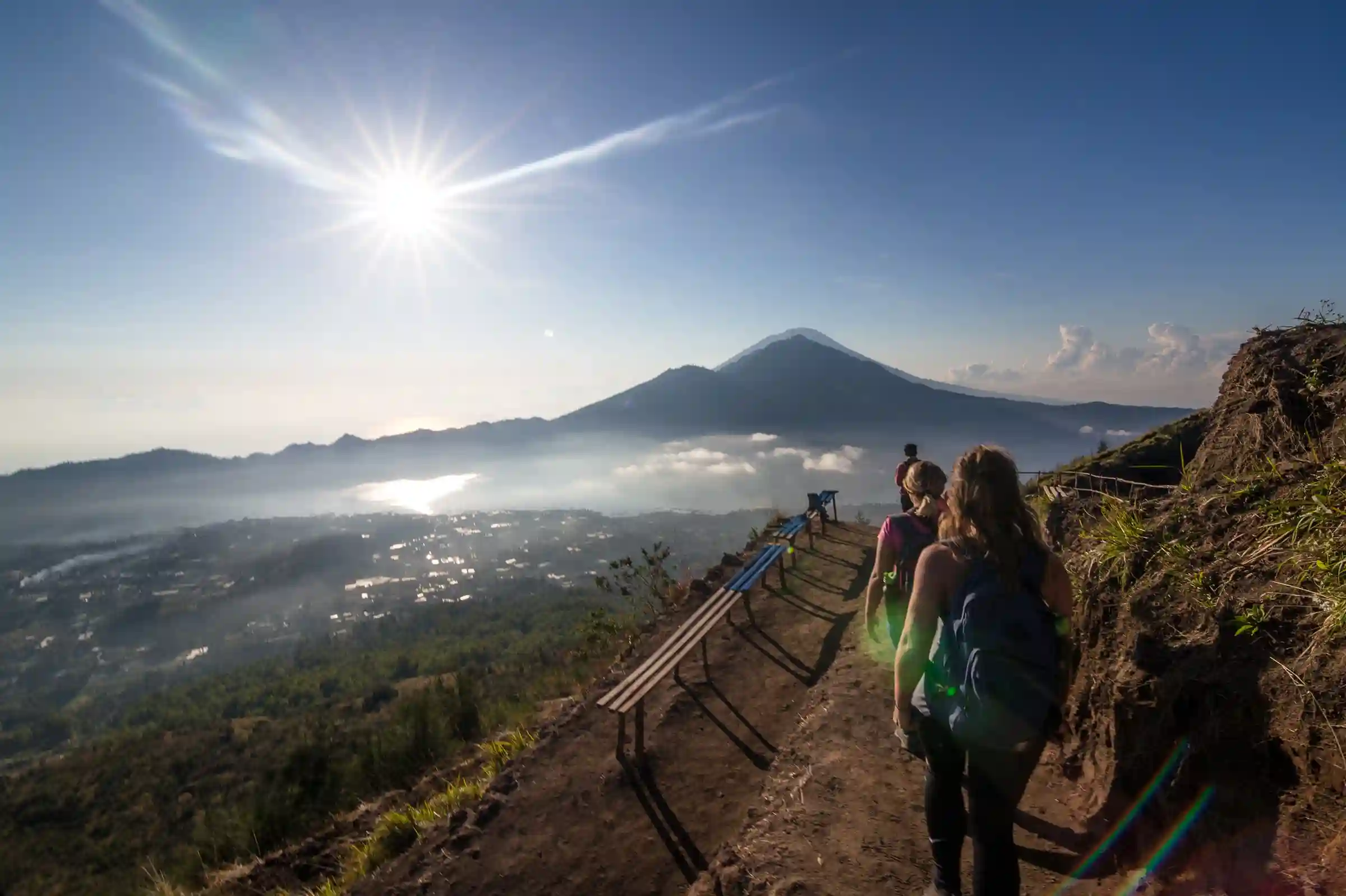 Dua orang sedang trekking di pagi hari di jalur Gunung Batur, salah satu spot pendakian gunung untuk pemula dengan pemandangan matahari terbit yang memukau.Ask ChatGPT 