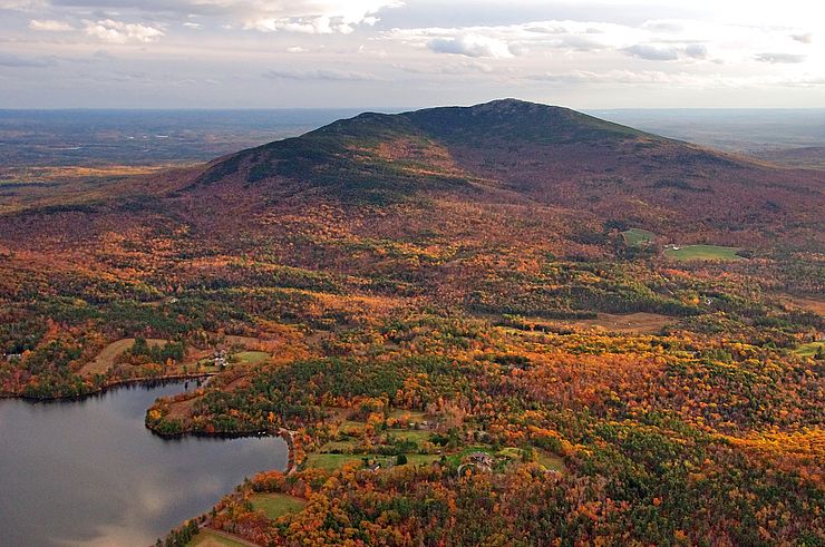Pendaki menyusuri jalur berbatu di Mount Monadnock yang dikelilingi pepohonan musim gugur, gunung ini dikenal sebagai salah satu lokasi pendakian gunung untuk pemula di Amerika Serikat.