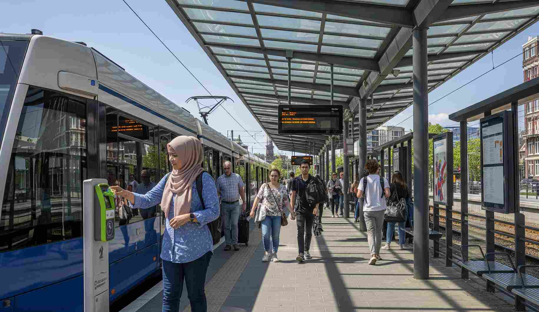 Seorang wisatawan Indonesia yang mengenakan hijab sedang menggunakan OV-chipkaart untuk menaiki trem di stasiun yang modern di Belanda. Belanda adalah negara ramah backpacker yang dikenal dengan sistem transportasi umum yang efisien dan mudah digunakan.